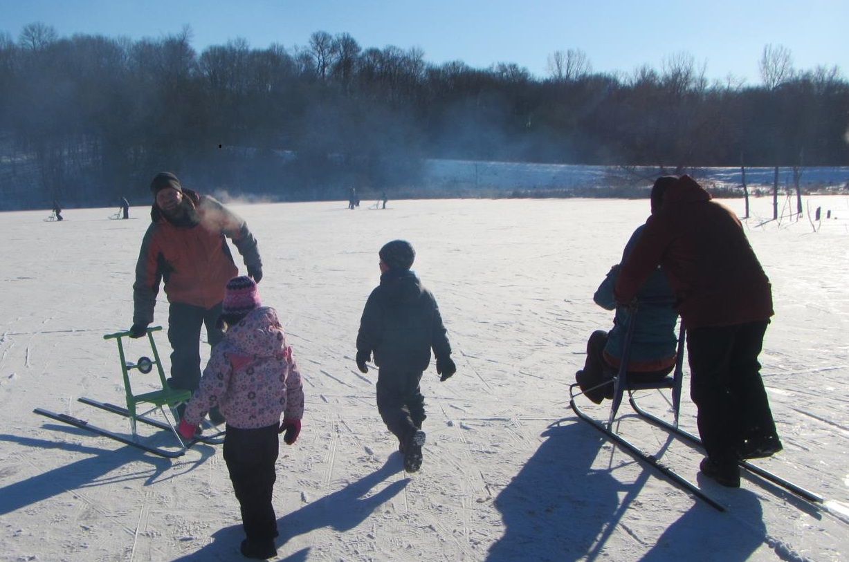 Adults and children enjoying using kick sleds